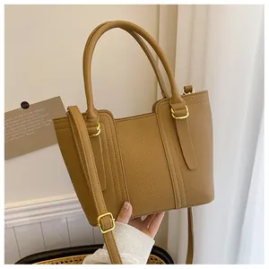 Detail view of brown pebbled leather bucket bag with gold hardware and hand handle