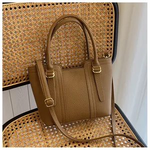 Detail of brown pebble grain leather bucket bag with gold hardware on a rattan chair