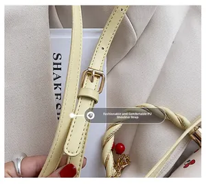 Detail of light yellow PU handbag with adjustable strap and woven handle with cherry charm
