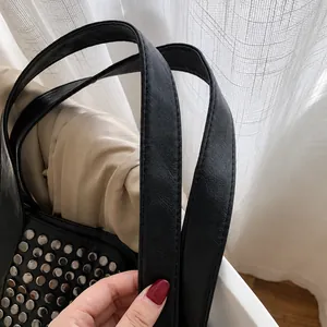Λεπτομέρεια από τις ενισχυμένες διπλές λαβές μιας μαύρης τσάντας με τρούκς και φυσική υφή δέρματος