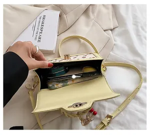 Detail of light yellow leather crossbody bag showing interior storage and cherry charm