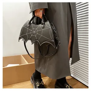 Detail of gothic bat-shaped handbag featuring white spiderweb contrast stitching texture