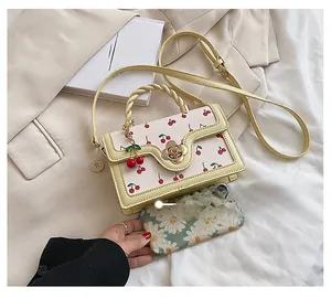 Detail of white cherry print handbag with wave edge flap and flower metal lock