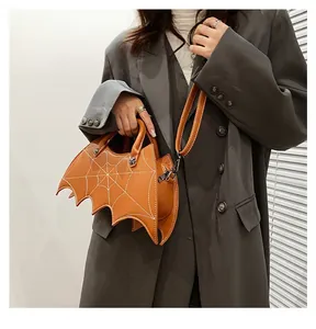 Detail of yellow bat-shaped PU handbag with white embroidered cobweb pattern and strap