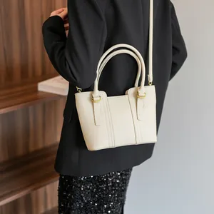 Fashionable beige pebbled leather bucket bag with dual handles and adjustable strap