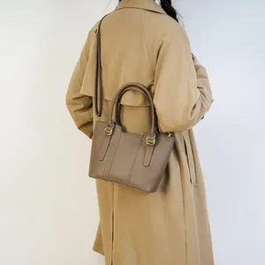 Brown litchi grain bucket bag with round handles and adjustable strap on khaki coat