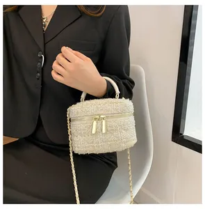 Detail van elegante crème tweed crossbodytas met gouden dubbele ritsen en een kettingriem