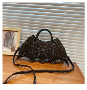 Detail of gothic bat-shaped bag featuring white spider web stitching and leather texture