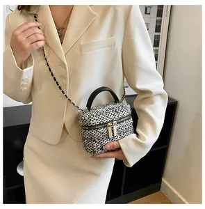 Detail van de zwart-witte tweed geweven textuur van een crossbodytas met goudkleurige hardware