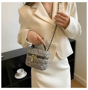 Detail van elegante zwart-witte tweed crossbodytas met gouden kettingriem