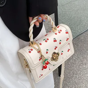Chic cream crossbody bag with cherry prints, floral lock and twisted top handle