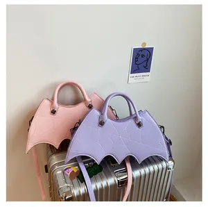 Close-up of pink and purple bat-shaped punk bags with web stitching and black rivets