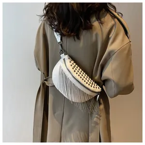 Détail du sac ceinture en cuir blanc avec clous noirs et franges de chaîne argentées