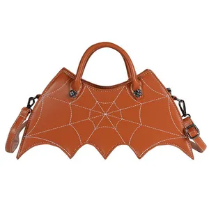 Close-up of brown bat-shaped PU leather bag with intricate white spider web embroidery
