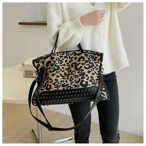 Detail view of leopard print tote bag featuring metallic rivets and black leather trim