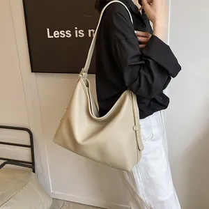 Modello che indossa una grande borsa hobo color crema con texture in pelle per il pendolarismo