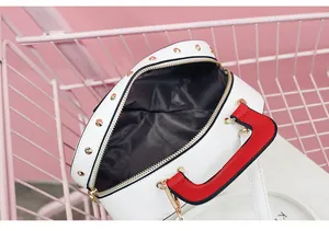 Detail einer weißen runden Tasche mit roten Griffen und Goldnieten im Einkaufswagen