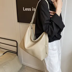 Dettaglio della borsa hobo color crema con morbida texture litchi e tracolla larga su modella