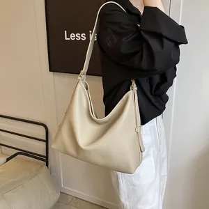 Dettaglio della borsa tote color crema in pelle martellata indossata a spalla