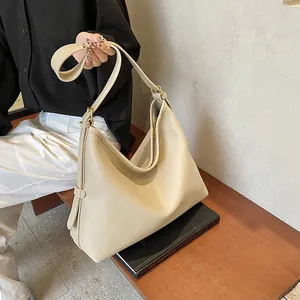 Dettaglio della borsa tote in pelle martellata beige con tracolla regolabile su panca