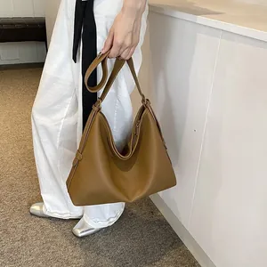 Dettaglio laterale borsa hobo in pelle marrone con cinturino decorativo in stile minimal