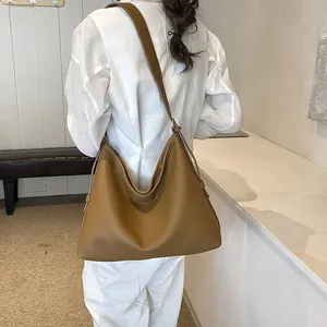 Dettaglio di una borsa tote in pelle marrone con texture a grana e coulisse laterale