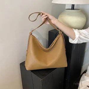 Dettaglio borsa tote in pelle marrone con grana e hardware dorato su piedistallo