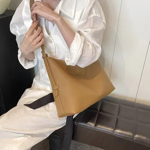Borsa tote in pelle marrone con trama litchi indossata da modella in interno minimalista