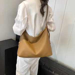 Vista laterale della borsa tote caramel con trama litchi indossata sulla spalla del modello