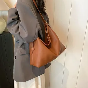 Borsa hobo in pelle marrone con texture morbida e tracolla larga indossata da una modella