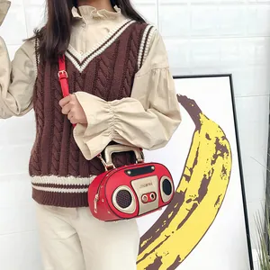 Rote Handtasche im Retro-Radio-Design mit Nieten und goldenem Griff über der Schulter