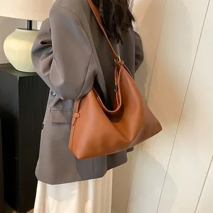 Modella che indossa una borsa hobo marrone con motivo litchi e tracolla regolabile