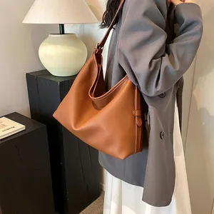 Dettaglio di una borsa tote in pelle marrone con tracolla larga e grana martellata