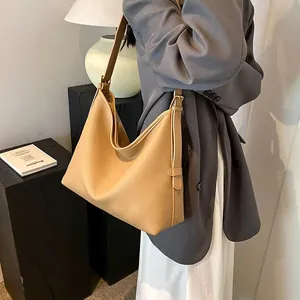 Dettaglio borsa tote in pelle beige con grana litchi e tracolla regolabile su modella