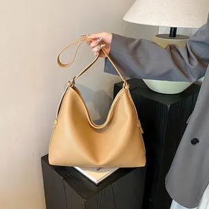 Dettaglio di una borsa hobo in pelle marrone chiaro con trama litchi e tracolla regolabile