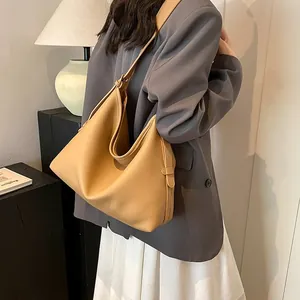Borsa hobo in pelle martellata caramello indossata a spalla in un interno sobrio