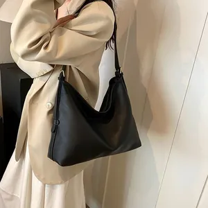 Dettaglio della borsa hobo in pelle nera martellata su modella con anelli in oro