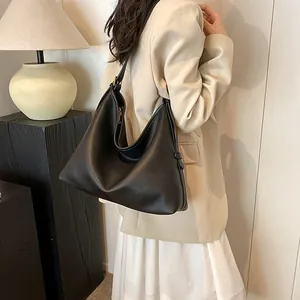 Dettaglio borsa hobo in pelle nera martellata indossata con tracolla larga casual