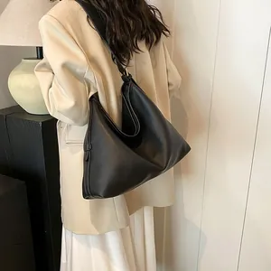 Dettaglio della borsa Hobo nera in pelle testurizzata indossata a spalla da donna