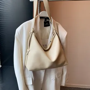 Dettaglio della pelle a grana di litchi crema e tracolla larga sulla borsa hobo minimalista