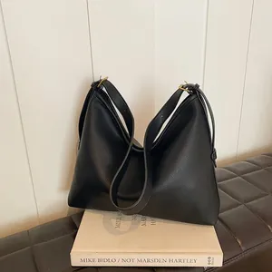 Dettaglio borsa hobo in pelle nera a grana litchi con fibbie dorate e doppi spallacci