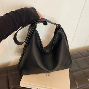 Dettaglio borsa tote in pelle martellata nera con tracolla larga e fibbie dorate eleganti