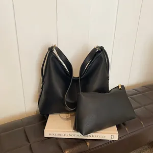 Dettaglio della borsa hobo in pelle nera martellata e pochette con finiture dorate