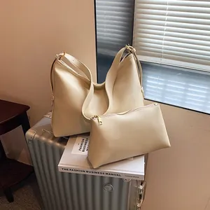 Borsa tote retrò bianco crema in pelle con ampia tracolla su una valigia d'argento