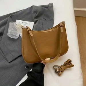 Detail of brown faux leather half-moon bag featuring NO FILTER embossing and adjustable strap