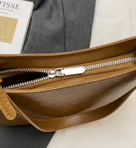 Detail of silver metal zipper closure on a brown textured leather underarm bag