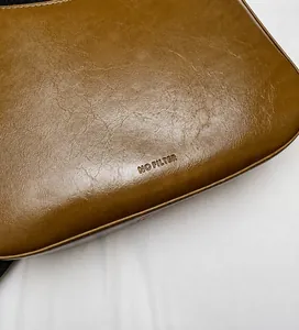 Close-up of brown pebbled PU leather bag featuring the embossed NO FILTER text detail
