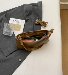 Detailed interior of minimalist brown leather shoulder bag showing zipper pocket and capacity