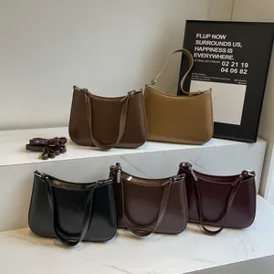 Detail of minimalist leather crescent shoulder bags in five colors on marble steps