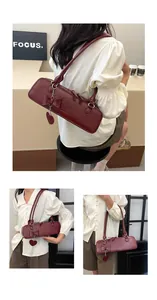 Dettaglio borsa baguette bordeaux con fiocco in pelle e ciondolo a forma di cuore